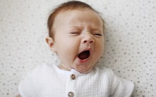 A 4 month old baby girl yawning in crib