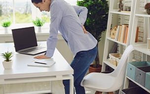 Women standing at a desk holding her back with Sciatica pain