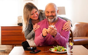 A diabetic patient checking his blood sugar at home with the support of his wife.