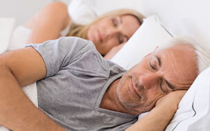 Senior man and woman sleeping together in their bed