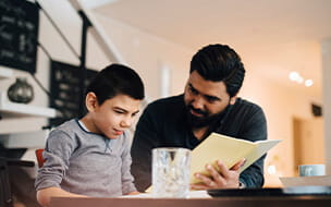 Father teaching autistic son sitting at kitchen table