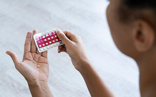 Close-up of young woman's hand holding birth control pills