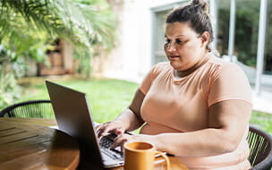 A mid adult overweight woman working on the laptop at home