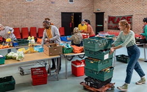 Group of volunteers organising food donations onto tables at a food bank