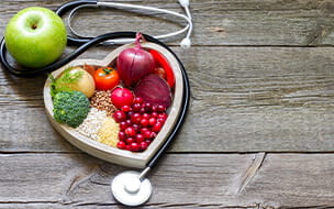 Healthy food in heart shaped bowl with stethoscope on vintage boards