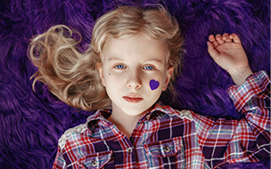 Young girl laying down with heart sticker on cheek
