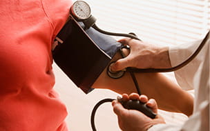 Doctor taking a blood pressure reading using a cuff and stethoscope