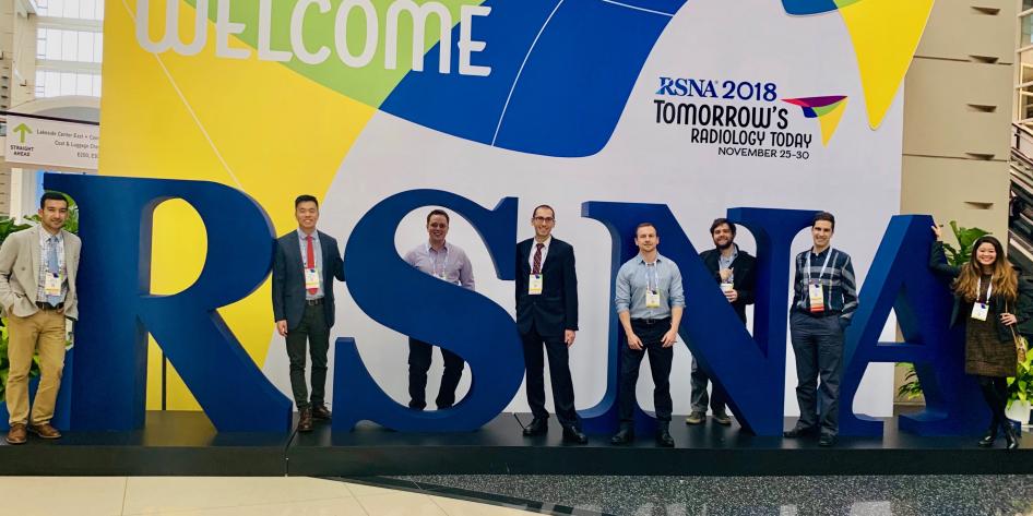 Large sign of RSNA Logo with row of radiology residents standing in front