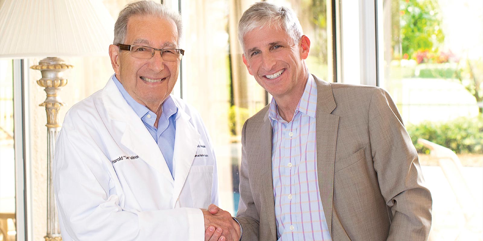 Sam Minoff (left) wearing his white coat from the 2018 Mather Society induction ceremony with Daniel I. Simon, MD
