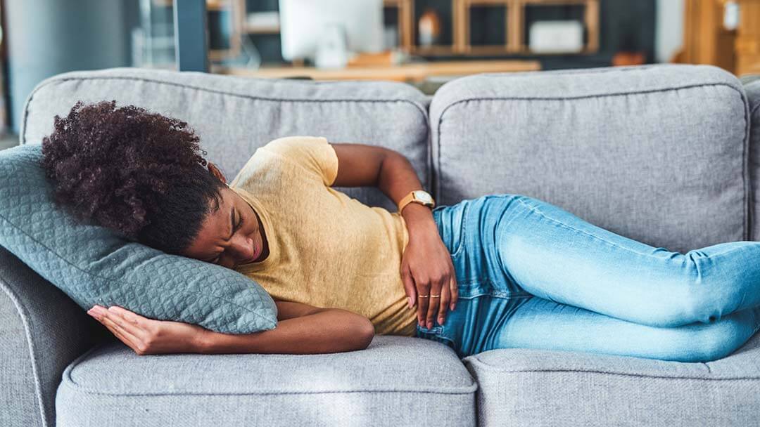 woman holding her stomach on couch