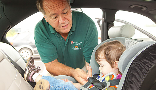 Man buckling a child into a car seat.