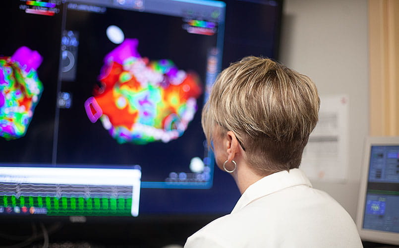 A provider examines a heart scan on a series of monitors