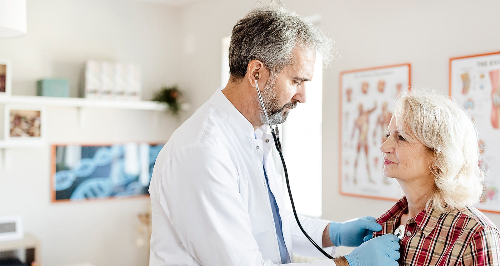 Doctor with a stethoscope checking the chest of a senior woman at the hospital
