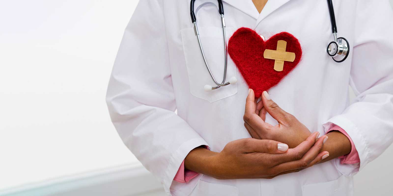 Doctor with a stethoscope holding a fabric heart