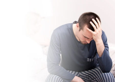 A distressed man sitting on the edge of the bed
