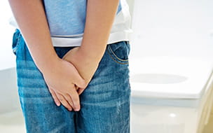 little boy with hands on groin area as if he needs to go to the bathroom