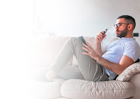 A man smoking while using digital tablet on sofa at home