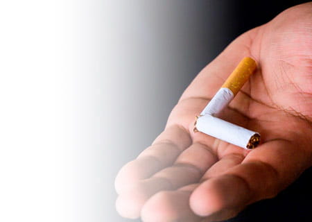 An outstretched hand holding a broken cigarette