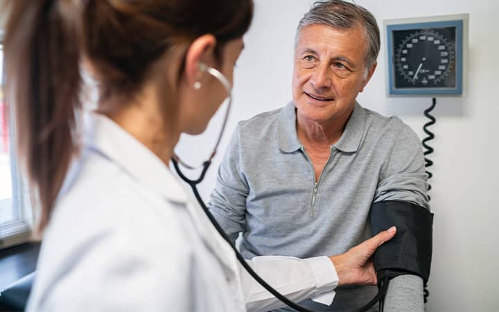 elderly patient at doctor's office with blood pressure monitor ECG machine and medication log