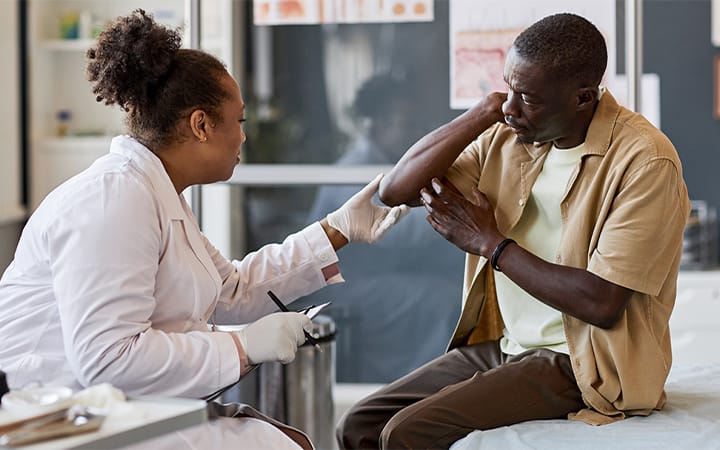 A female dermatologist examines a male patient’s skin