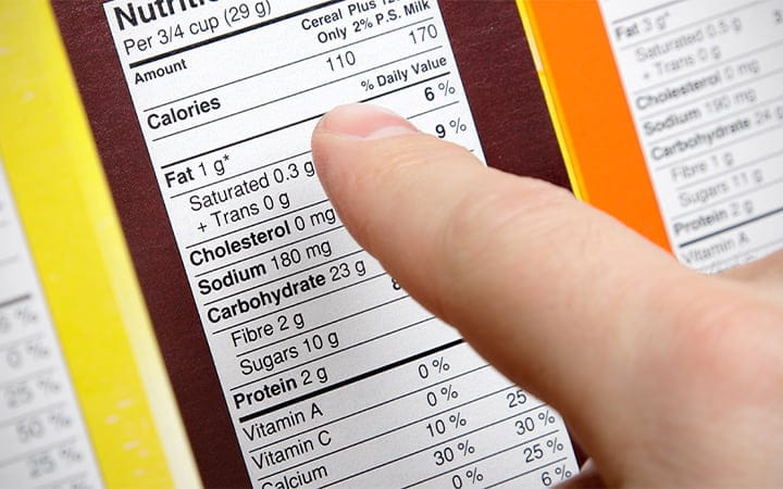 A shopper compares the nutrition labels of various boxes of cereal