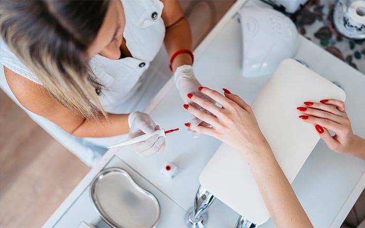 A young woman getting her nails done by a female nail technician at the beauty salon