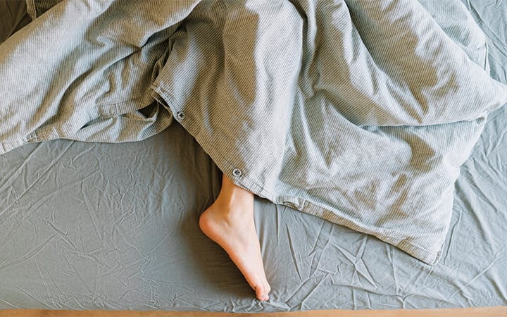 The lower half of a woman lying in bed