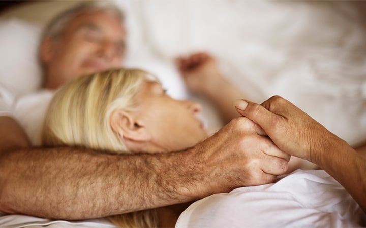 A mature couple embracing in bed