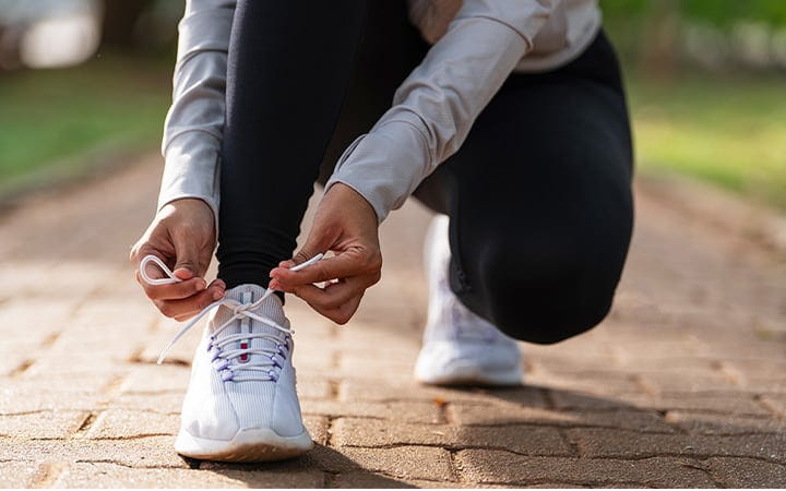 A closeup of a female runner getting ready for jogging outdoors on a forest path on an autumn morning