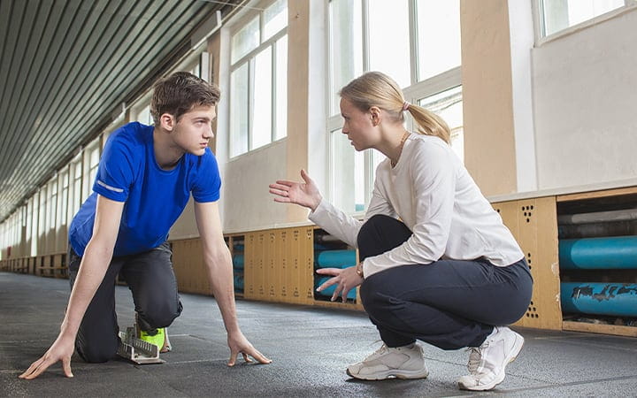 A teenager training under the guidance of his coach in a gym