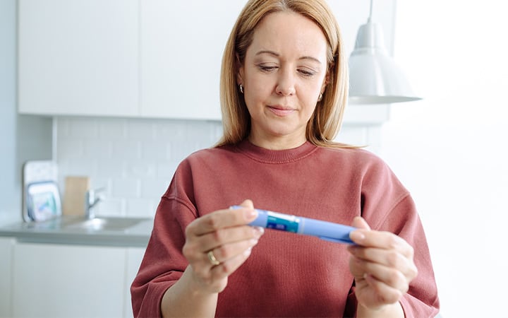 A woman examines an insulin pen