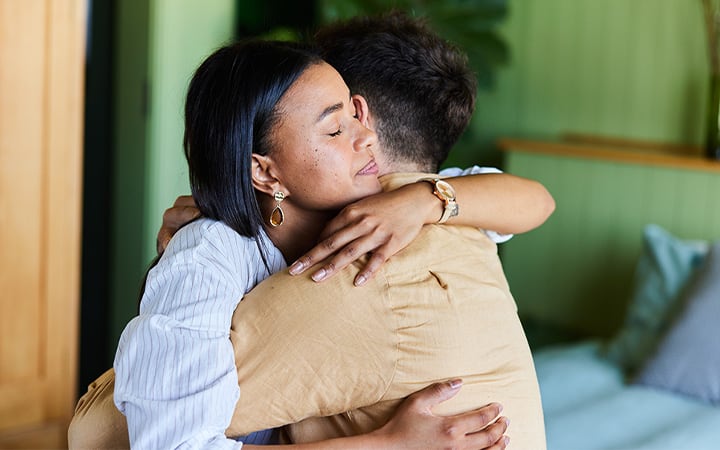 A young woman consoling a man with a hug while sitting together
