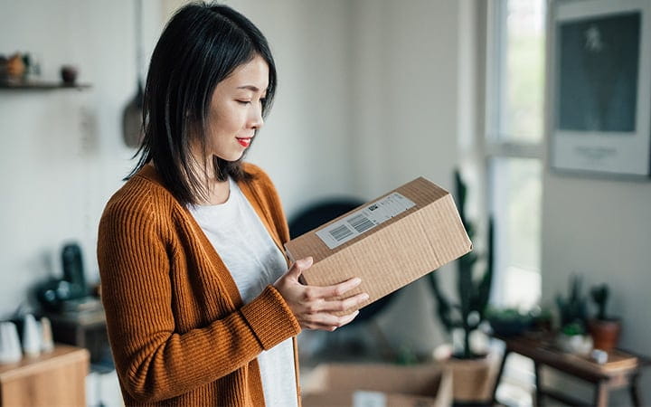 A young woman is checking the delivery label on a package