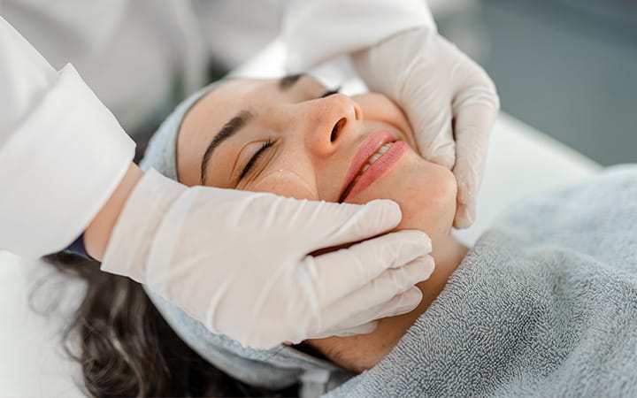 A smiling, relaxed woman receiving a beauty treatment