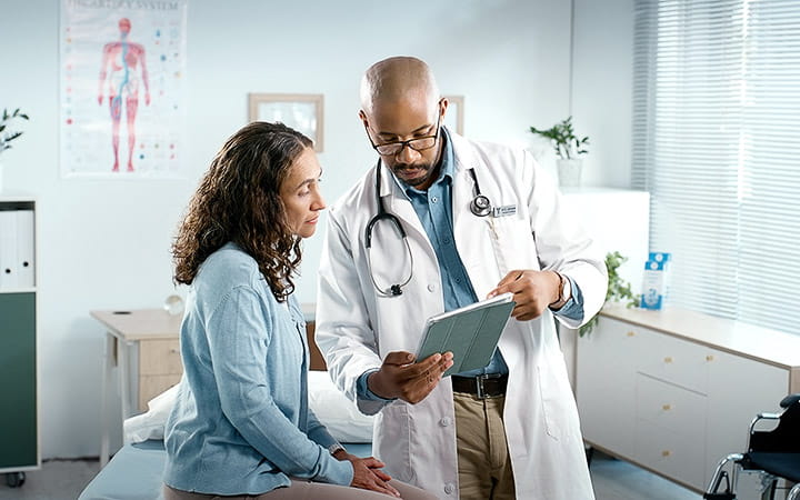 A patient consults with her cardiologist, who reviews her treatment plan on a digital tablet