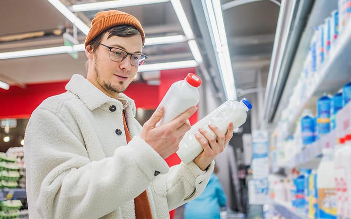 man compares milk cartons at store