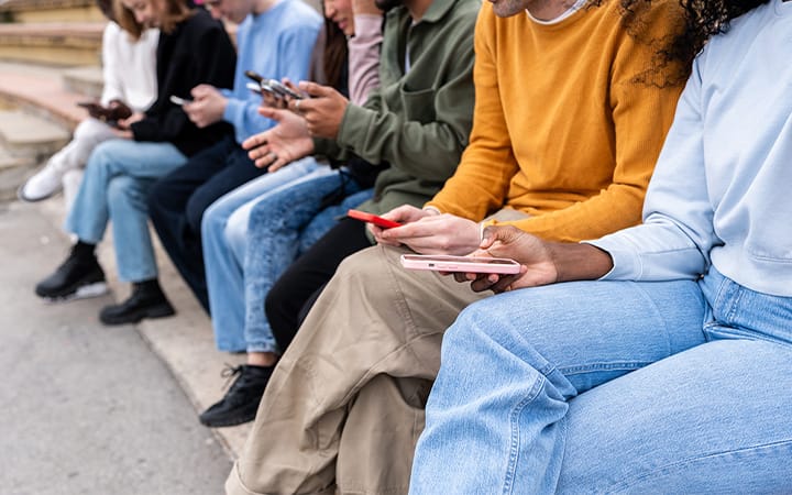 A group of young people using smartphones while sitting on urban steps