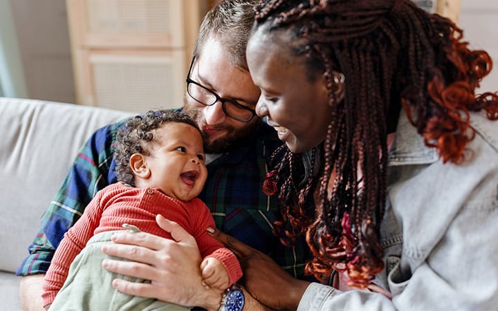 Happy parents sitting on a couch with their baby boy