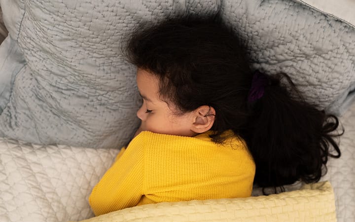 A young girl soundly sleeping under a weighted blanket