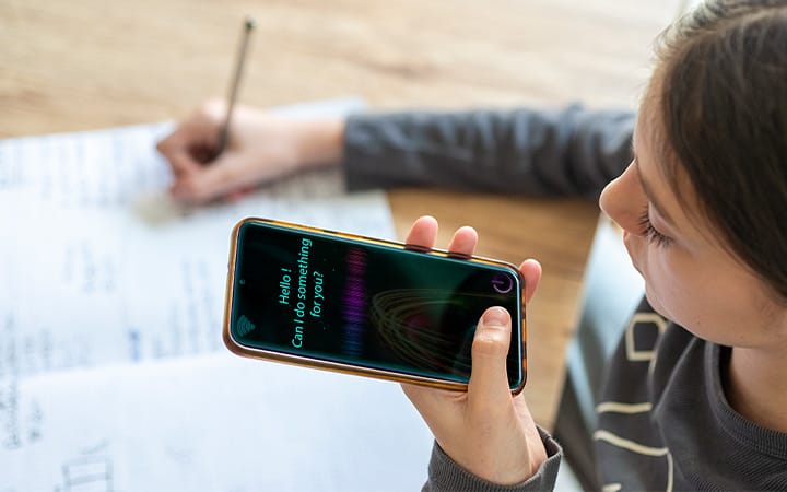A young girl using an AI virtual assistant on her phone to help with schoolwork