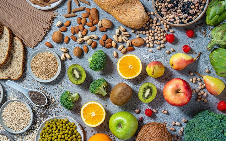 Vegan food arrangement including fruits and vegetables, seeds beans, whole grain carbohydrates, nuts and legumes