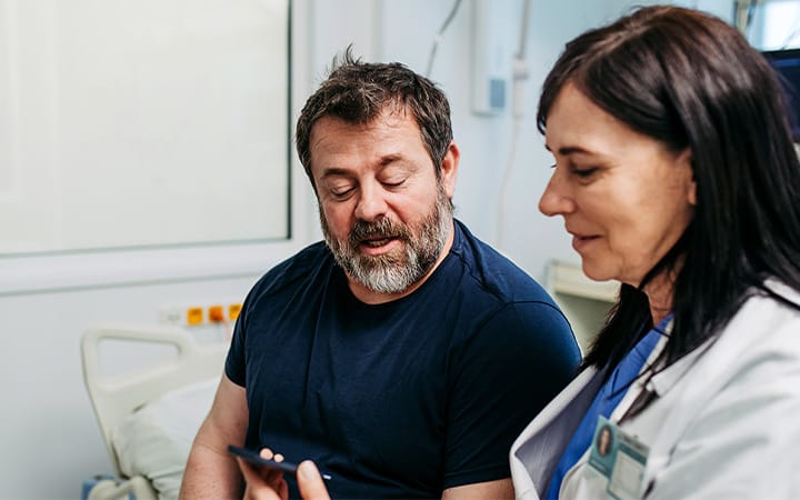 A doctor teaching a diabetic patient how to use a continuous glucose monitor with a smartphone app