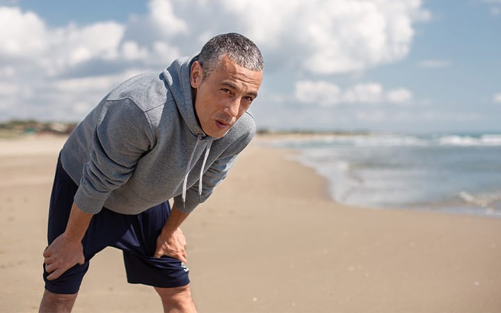 A man out of breath after running on the beach