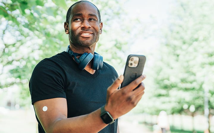 A young man checking his mobile phone while standing in a park during a workout