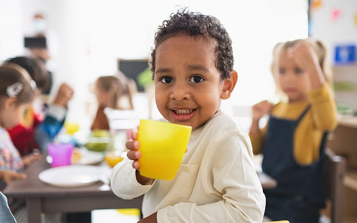 smiling child drinking from cup at school lunch