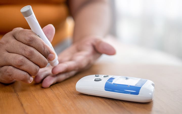 a person pricking their finger with a lancing device to check their blood sugar 