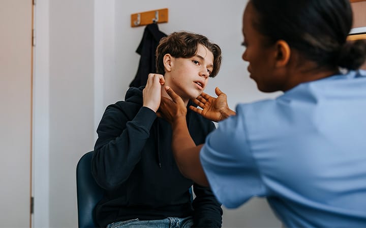 Doctor examines teen boy's throat