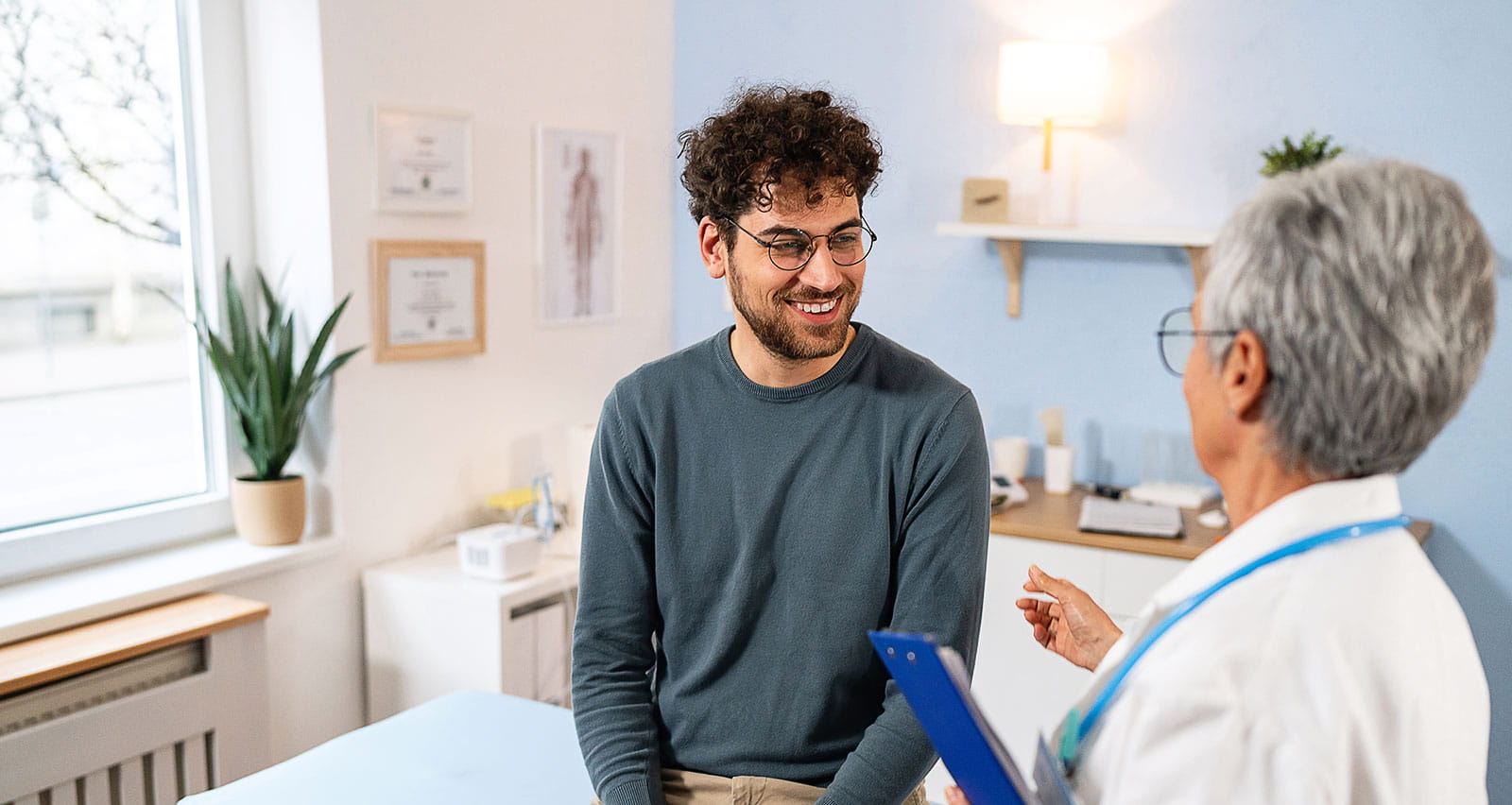 A male patient having an annual medical check-up with a senior female primary care doctor
