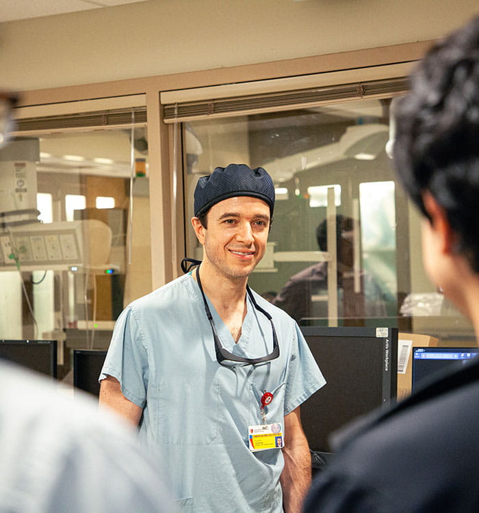Guillherme Attizzani, MD pictured in catheterization lab setting with colleagues at the forefront.