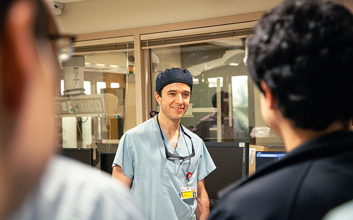 Guillherme Attizzani, MD pictured in catheterization lab setting with colleagues at the forefront.
